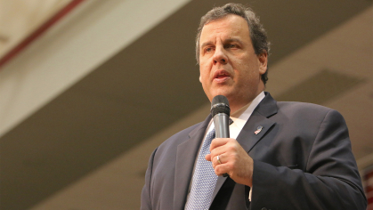 Former NJ Gov. Chris Christie standing with a microphone in hand