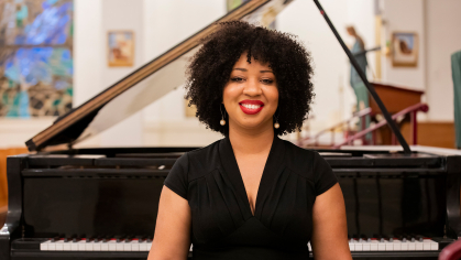 Courtney Bryan standing sitting in front of Piano