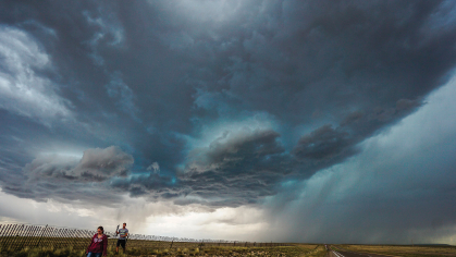 Two students walking below threatening dark clouds.