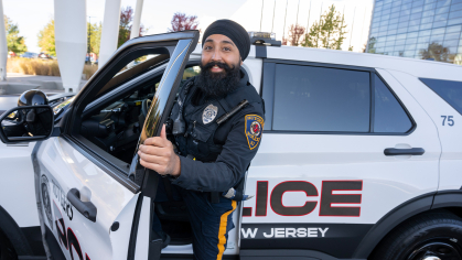 Gurwinder Singh standing next to Rutgers Police Car