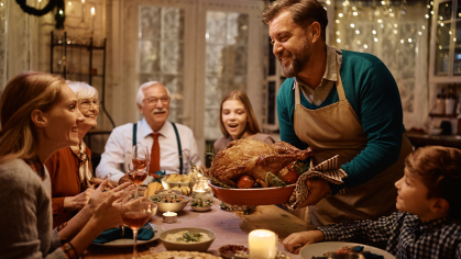 man holding thanksgiving turkey at the dinner table