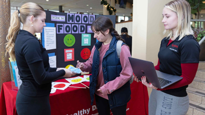 Undergraduate student researcher Claire Ostaszewski (left) holds cards for Sara Fajardo to select as fellow student researcher Holly Dorsett watches on during data collection regarding the connection between one's mood and food in Neilson Dining Hall in December.