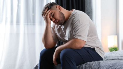 Man sitting on couch holding his head