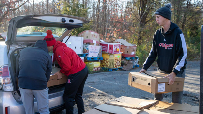 Rutgers men's golf team loads up a car with boxes of food for a local food bank. 