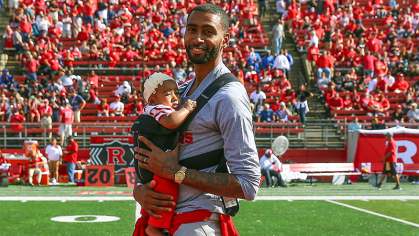 Quincy Douby standing with a baby in a carrier 