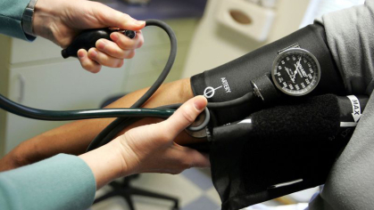 A health care provider using a blood press cuff