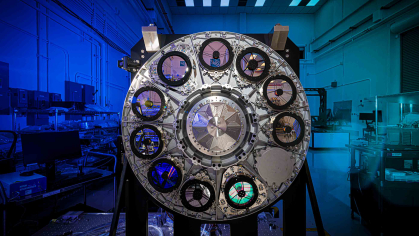 Stainless steel disk with with ten black circles on its perimeter with a blue background light and a lab setting.