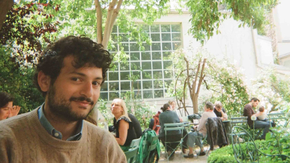 Tobias Robert Philip, who began his studies at Rutgers University-New Brunswick in 2020, sits outdoors in a shaded, patio area.