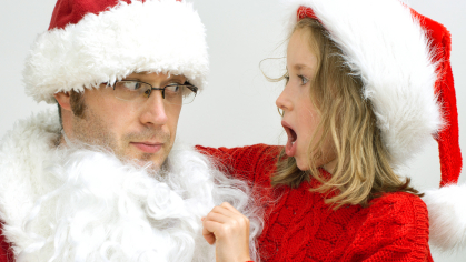 Child pulls down Santa's fake beard.