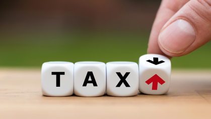 Lined up dice spelling out the word "tax" with the last die being an up and down arrow