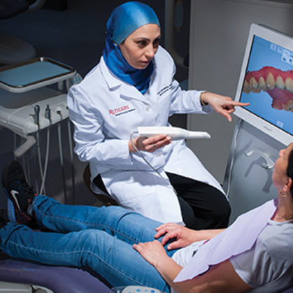 A dentist talking to a patient sitting in a chair
