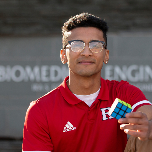 Dylan Sadiq (SOE '22) sits outside the biomedical engineering building holding a Rubik's Cube.