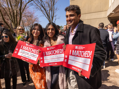 Robert Wood Johnson medical school students hold up signs identifying where they matched