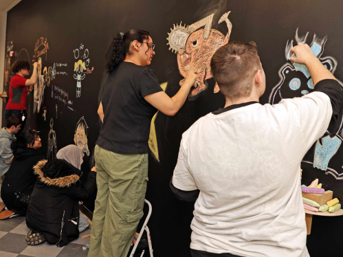 Students (from furthest left to right) Preston Romanienko, Andrew Hargy, Yumna Enver, Aman Kashmiri, Stayshey Sagastume-Castillo and Robin Mager draw on a collaborative chalkboard wall at the Mason Gross School of Arts on Monday.