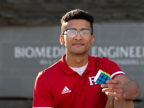 Dylan Sadiq (SOE '22) sits outside the biomedical engineering building holding a Rubik's Cube. 