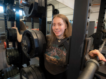 Naomi Kutin surrounded by weightlifiting equipment at Rutgers