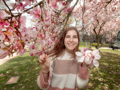Talia Rosen standing in the pink blossoms of a tree
