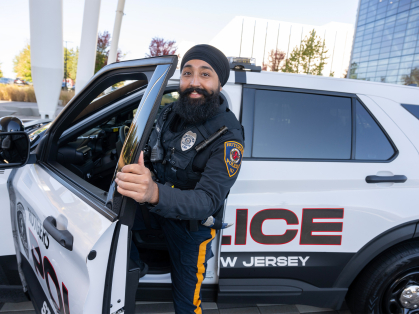 Gurwinder Singh standing next to Rutgers Police Car