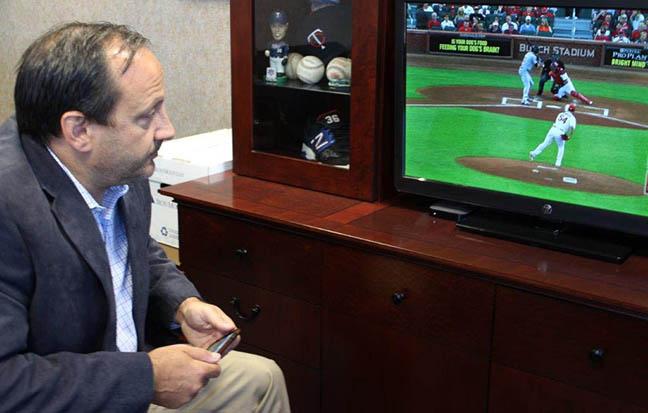 Image of Dave Pepe watching his baseball clients on TV.