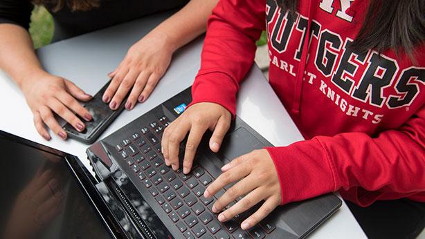 Rutgers Today, Rutgers news - Office of Financial Aid, student in Rutgers sweatshirt types on laptop