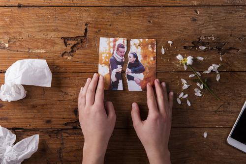 Hands ripping photo of couple in half