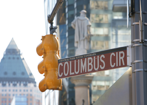 Columbus Circle street sign with statue of Christoper Columbus in the background