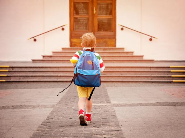 Child with backpack walking up to school