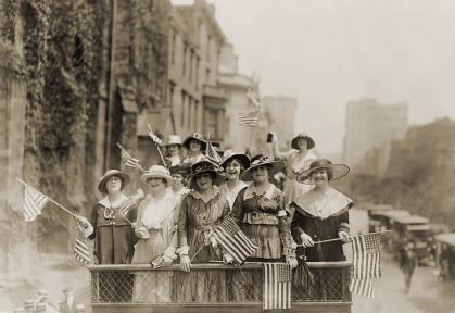 Women standing with American flags on top of a truck