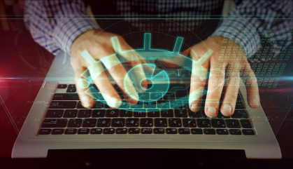 An eye over a laptop that indicates spyware