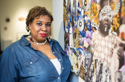 Artist Lavett Ballard standing next to one of her paintings