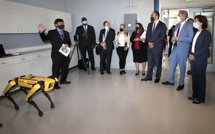 Leaders touring a robotics lab and meeting a robot dog