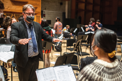 From a stage within Nicholas Music Center at Rutgers University–New Brunswick, Kynan Johns leads undergraduate students.