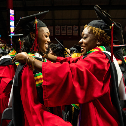 two students draping Kente stoles on one another