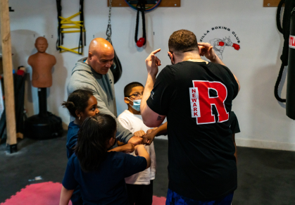 Isnard Mir-Merced in a huddle with young Zilla Boxing Club students