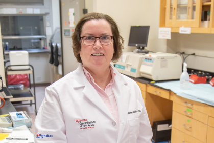 Eileen White wearing a white lab coat standing in a lab