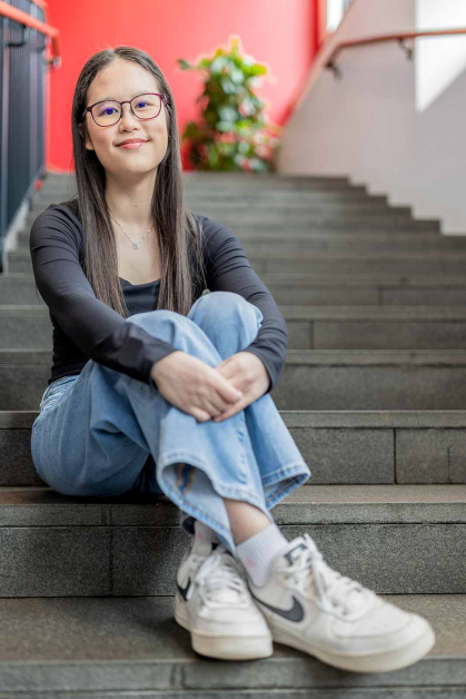 Amelia Khoo sits on stairs inside the Honors College at Rutgers-New Brunswick.