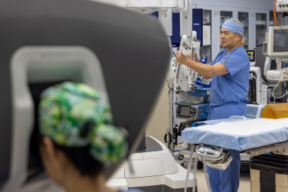 surgeon works at console while the other adjusts robot