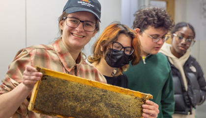 Four students display rectangular wood frame.