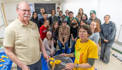 Man and woman at front of classroom with students at the back