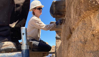Johanna Cordasco kneels on scaffolding to apply an adobe mixture to a wall of Bent's Old Fort in southeastern Colorado, where AmeriCorps members worked to help restore the former fur trading post.