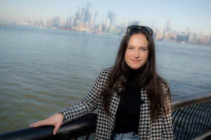 Mary McGowan at New Jersey waterfront with New York City in background.