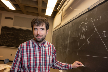 Maxime Van de Moortel writes math equations on a chalk board