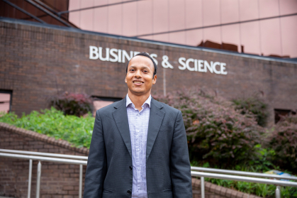 Sheikh Rabiul Islam standing in front of a building with a sign that reads business and science