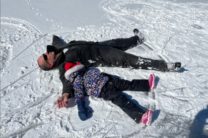 Father and child making snow angels