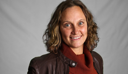 woman in a red turtleneck and brown leather jacket against a white background