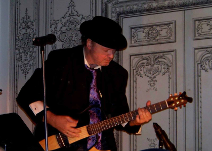 Singer-songwriter Mike Kovacs plays a guitar during a performance.