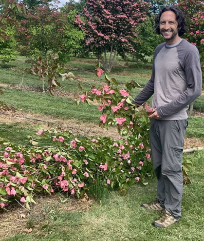Man at right stands in a dogwood orchard