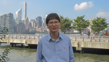 Man standing in front of a bridge with a skyline behind him