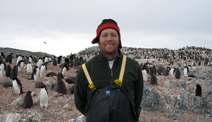 Man standing in field with penguins behind him