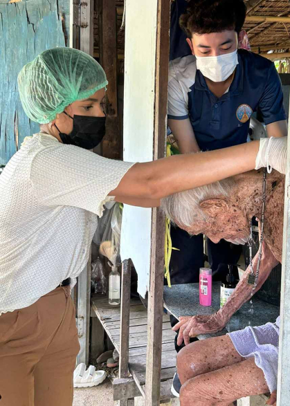 Rutgers student Maira Salim (left) and a registered nurse tend to an elderly man in the Maha Sawat subdistrict outside of Bangkok.